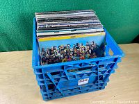 Blue milk crate filled with vinyl records on table