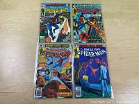 Four issues of The Amazing Spider-Man comics vol.1 laid out on wood surface showing covers and colorful artwork