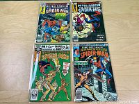 Four Spider-Man comic books on a wooden surface including issues 15, 37, 62, and King Size Annual No. 2.