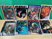 Eight EPIC Illustrated adult science fiction comic magazines arranged in two rows on green fabric background showing varied cover art