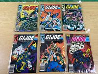 Top-down view of six Marvel G.I. Joe comic books in plastic sleeves arranged on a wood surface.