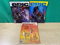 Three Marvel Epic Illustrated magazines issues 1, 2, and 3 displayed upright on a wooden surface with green fabric background.