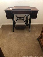 Full view of antique Singer sewing machine with wooden cabinet closed and cast iron treadle base visible