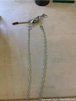 Manual chain come-along with metal chain sections and red handle