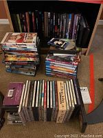 Overall view of DVDs and CDs arranged on floor and shelf, showing many DVD movie cases stacked and CDs organized in rows.