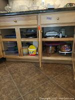 Cupboard containing various bowls, containers, and some kitchen appliances.