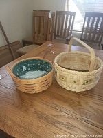 Photo of two handwoven Longaberger baskets on wooden table with chairs in background showing overall appearance and details.