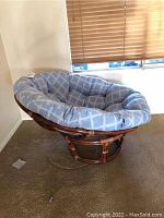 Large papasan chair with a blue and white checkered cushion on a natural dark wicker base seen from an angle.