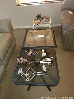Three glass top tables with various wind chimes and decorative items placed on and around them including owl and bird figurines.