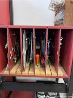 Photo of slide-out storage compartments filled with various metal hand tools stored vertically including clamps, pliers, and wrenches.