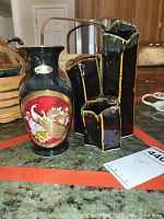 Two Asian style glass vases on a table, one with a red crane design and one with an abstract geometric shape.