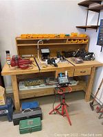 Front view of wooden workbench with items on surface and shelving back panel with yellow bins.