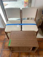Two padded chairs with light upholstery and a wooden storage cabinet from above, showing the seat and top surfaces.
