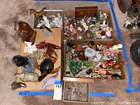 Wide shot of three boxes containing mixed small figurines and front items on cardboard