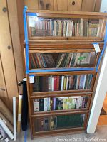 Front view of large wooden barristers bookcase filled with books, showing four glass door compartments with blue tape.