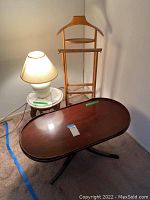 View of the coffee table, valet stand, side table and table lamp grouped together in a corner on carpet.
