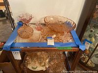 Photo showing all pink vintage glass items on a table including a large bowl, covered dish, small pitcher, compote dish, and basket-shaped piece.