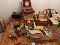 Wide shot showing the wooden cigar boxes, vintage camera, small figurines, and additional assorted household items arranged on a wooden table.