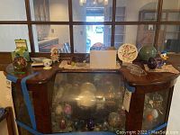 Top of cabinet view showing assortment of decorative eggs, plates, paperweights and figurines on furniture
