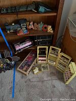 View of shelf unit with a model steam locomotive, 'MAGIC' wooden blocks with cactus and horse, boxed model train cars, and open yellow chemistry set cabinets with chemical bottles and lab tools on the carpeted floor.