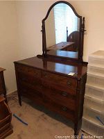 Full view of vintage wooden dresser with large mirror attached showing ornate carved wood and drawer handles.
