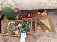 Photo showing multiple boxes on carpet with assorted rocks, mineral chips, colorful glass marbles, plastic game chips and uniquely shaped stones.