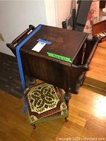 Dark stained wooden side table with a rectangular top showing wear, equipped with side handles and compartments underneath for magazines. Dimensions labeled as 24 x 13 x 27 inches.