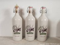 Three white ceramic beer bottles from Beau's All Natural Brewing Company with lug tread design and swing-top lids.