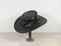 Black leather bush hat angled to show the side and top with a slight curve on brim and crown detail.