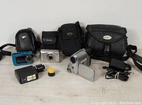 Full lot overview showing all cameras, cases, flash, and accessory container