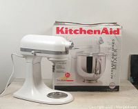 White KitchenAid Accolade 400 tilt head mixer with chrome detail, shown next to its original box on a wooden table.
