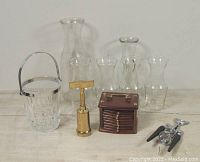 Full lot view showing six glass carafes, small glass ice bucket with metal handle, brass corkscrew, wooden coaster holder with coasters, and chrome bottle opener/corkscrew.