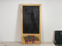 Front view of rustic wooden chalkboard with black writing area and colorful pig butcher cut graphic at bottom.