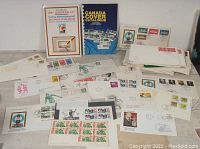 Overall lot showing sports-themed First Day Covers spread out, Canada Cover Catalogue book, Curling Württemberg sheet, and envelopes with stamps and postmarks.
