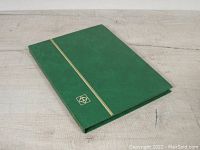 Green hardcover organizer book with gold accent and emblem detail on front cover.