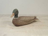 Side angle showing full length and painted detail of the carved wooden duck decoy with green head and brown body feathers.