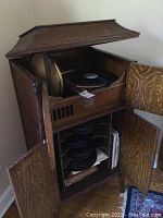 Open oak cabinet showing top shelf turntable and lower record storage