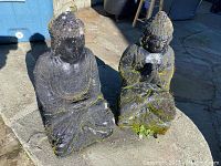 Both concrete Buddha statues side by side on stone surface