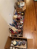 Overview of boxes lined up on floor showing large volume of assorted candles and holders