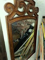 Front view of the hardwood framed wall mirror showing rectangular shape and wood scroll ornamentation at top.