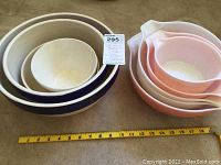 Three white interior stoneware bowls nested with a navy exterior largest bowl and ceramic mid-sized bowl