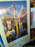 Framed skiing event poster showing two skiers, one holding skis, titled '10th Annual Ipaats-Bill Over the Hill Downhill'.