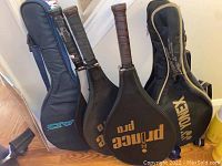 Photo of tennis and badminton rackets with cases, showing Prince and Yonex brands and condition of grips and covers.