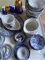 Overview of lot showing blue and white porcelain bowls, cups, pitcher, and Venetian cobalt blue glass decanter with gold gilding on white tray
