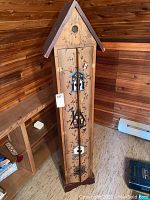 Full view of tall wooden bookcase shaped like a birdhouse with front doors painted with colorful birdhouse and floral tole art.