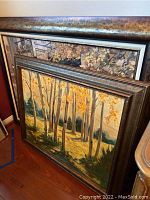 Two framed art pieces leaning against a wall showing the oil painting and print on canvas.