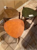 Set of 3 triangular stackable tables in orange, green, and brown colors, arranged on tile floor, showing overall wear and condition.