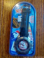 Photo of the watch sealed in its original clear plastic case with visible NASCAR, NFL, NHL logos on the packaging insert, showing the front face with #3 and Dale Earnhardt Sr name.