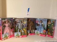 Five boxed Wizard of Oz themed Barbie dolls displayed side by side including Glinda, Tin Man, Cowardly Lion, Dorothy, and Scarecrow.