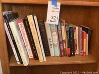 Photo of a shelf with assorted hardcover and softcover books featuring cookbooks, fiction novels, and biographies.